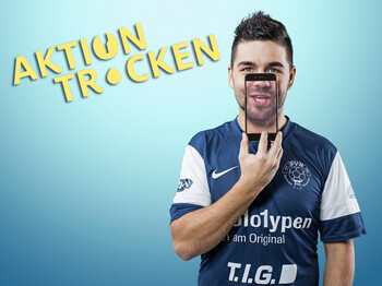 Ein junger Mann hält ein Handy über sein Gesicht, wobei man sein Gesicht durch das Handy sieht. Der Hintergrund ist hellblau und der Herr trägt ein blaues Fußballtrikot.