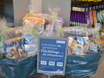 Hygienepakte im Wert von 5, 10 bzw. 20€ , die unterschiedliche Produkte wie Duschgeel und Shampoo beinhalten, stehen schön verpackt in einem Drogeriemarkt. Sie werden Flüchtlingen im ganzen Land unterstützen. 