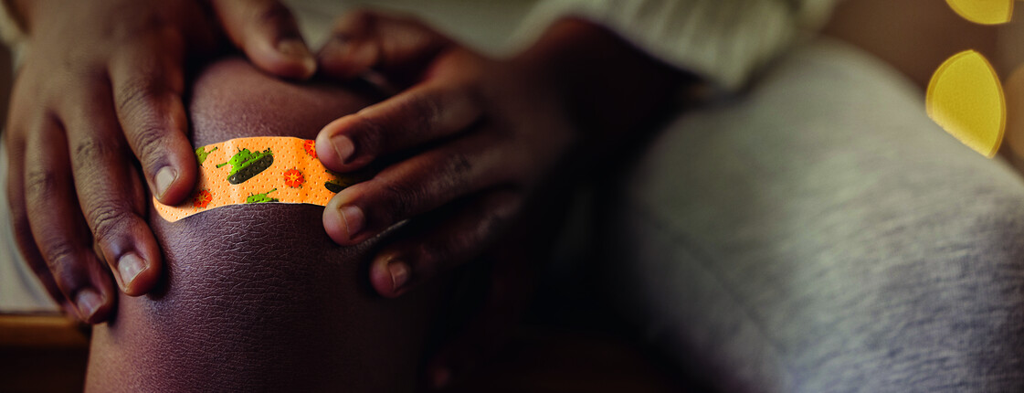 Shot of an unrecognizable child applying a bandaid to their knee at home
