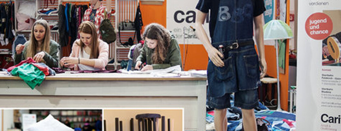 carla Adventmarkt: Kleidung und Stoffe werden hübsch bei einem Stand ausgestellt. Dazu verwendete man unter andrem eine Schaufensterpuppe. Auch sind am Stand drei junge Frauen, die mit Nähen beschäftigt sind. 