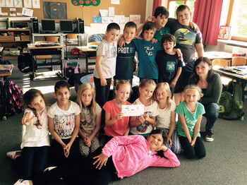 Die 3b Klasse der Volksschule Rankweil-Brederis steht mit Caritasmitarbeiterin Sabine Längle zu einem Gruppenfoto zusammen. Die Mädchen sind in der forderen, die Buben stehen in der Reihe. Der Hintergrund ziert ein gewöhnliches Klassenzimmer. 
