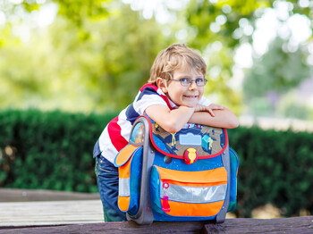 Happy little kid boy with glasses and backpack or satchel on his first day to school . Child outdoors on warm sunny day, Back to school concept. Kid with traditional schoolbag in German Schultuete Happy,Little,Kid,Boy,With,Glasses,And,Backpack,Or,Satchel