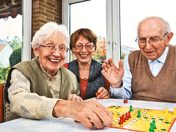 Drei alte Menschen spielen ein Brettspiel
