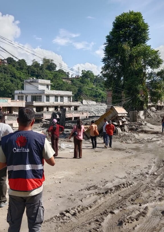 Caritas-Mitarbeitende begutachten eine von Schlamm und Geröll verwüstete Straße nach der Flut in Nepal.