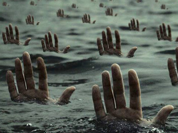 Fingerspitzen ragen aus dem Wasser. Es ist dunkel und düster belichtet. Es will auf die zigtausend Flüchtlingeaufmerksam machen, die auf ihrer Reise nach Europa ertrinken.