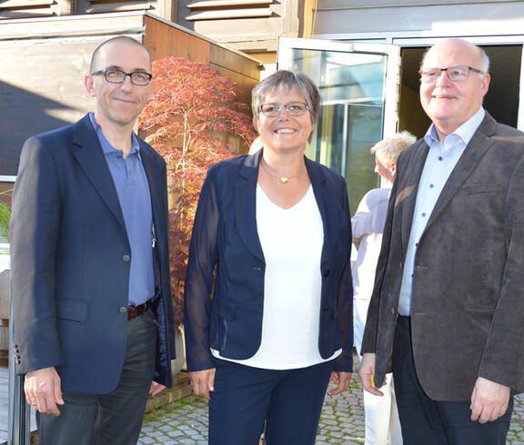 Walter Schmolly, Peter Klinger und eine Frau befinden sich im Freien für ein Gruppenfoto. 