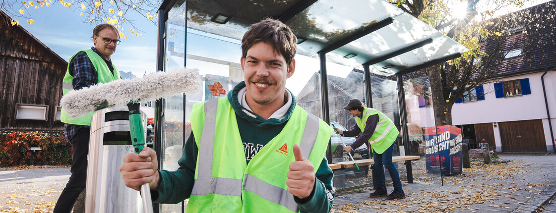 Menschen mit Behinderung reinigen Bushaltestelle