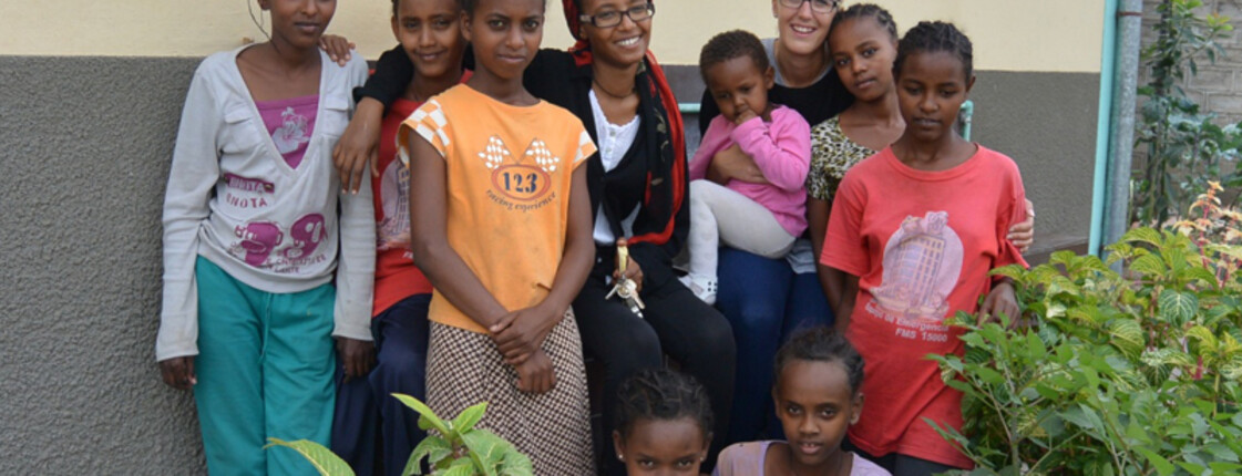 Gruppenfoto vor dem Girlshostel in Ähtiopien. Mädchen und junge Frauen posieren vor dem Hostel im Garten. Sie sind bunt in allen Farben gekleidet. 