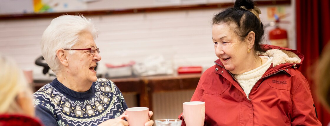 Einmal wieder ins Kaffeehaus gehen Vier Frauen sitzen an einem gedeckten Küchentisch. Sie trinken Kaffee und unterhalten sich.