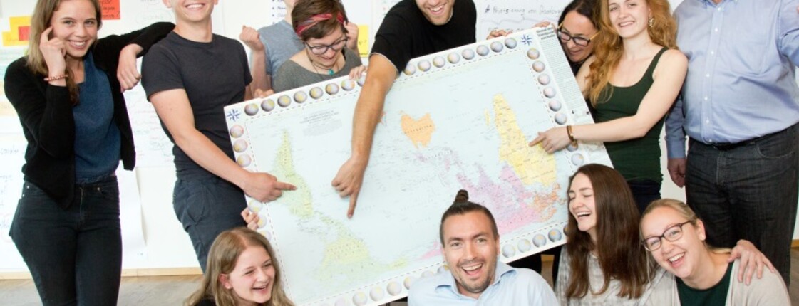Jugendliche um eine Landkarte versammelt