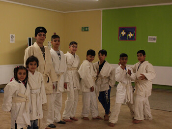 Die Flüchtlingskinder beim Judotraining. Alle tragen eine weiße Judouniform und stehen in einer Reihe. Manche schon in einer Judostellung. 