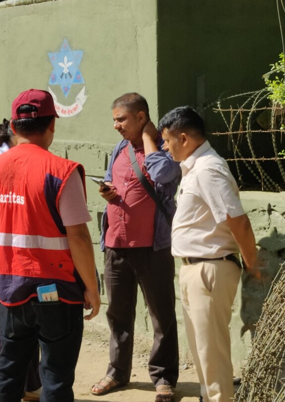 Ein Caritas-Mitarbeiter und weitere Personen besprechen die Lage in einem von der Flut betroffenen Gebiet in Nepal.