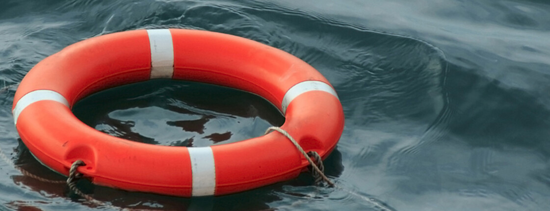 Ein klassischer roter Rettungsring aus Plastik schwimmt im Wasser. 