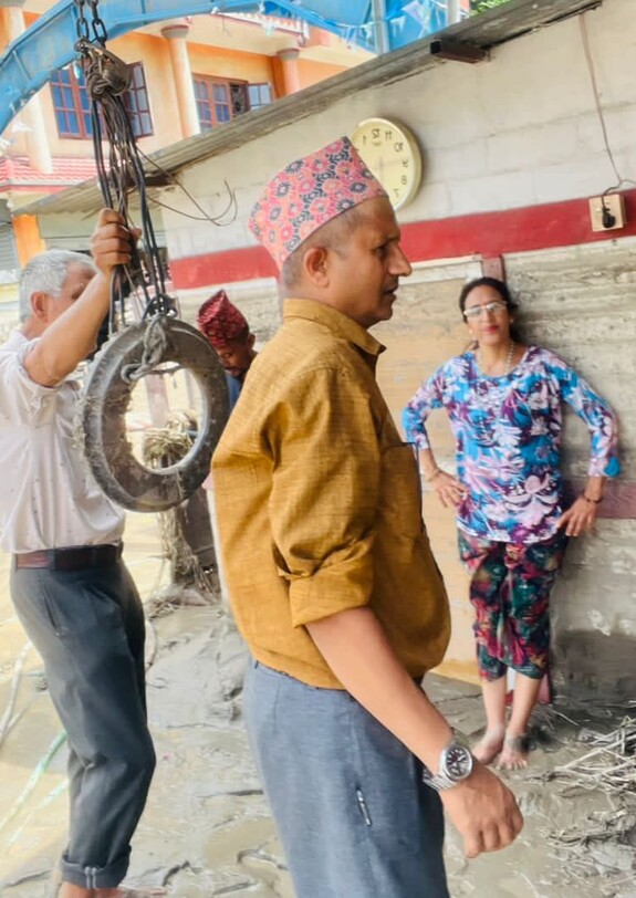 Mehrere Menschen stehen zwischen Schlammspuren und Gebäuden in einem von der Flut betroffenen Gebiet in Nepal.