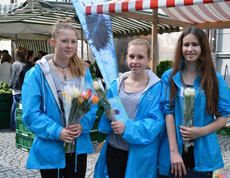 Drei junge Mädchen beim Verkauf von bunten Rosen für einen guten Zweck.