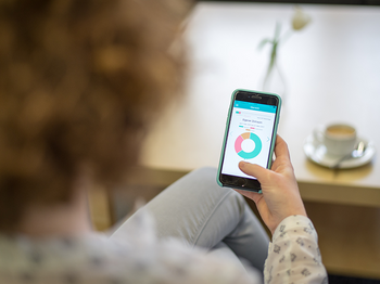 Eine Frau schaut sich die App "Aktion Trocken" auf ihrem Smartphone an.