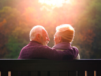 Senior,Couple,Sitting,On,Bench,In,Autumn,Park,And,Looking