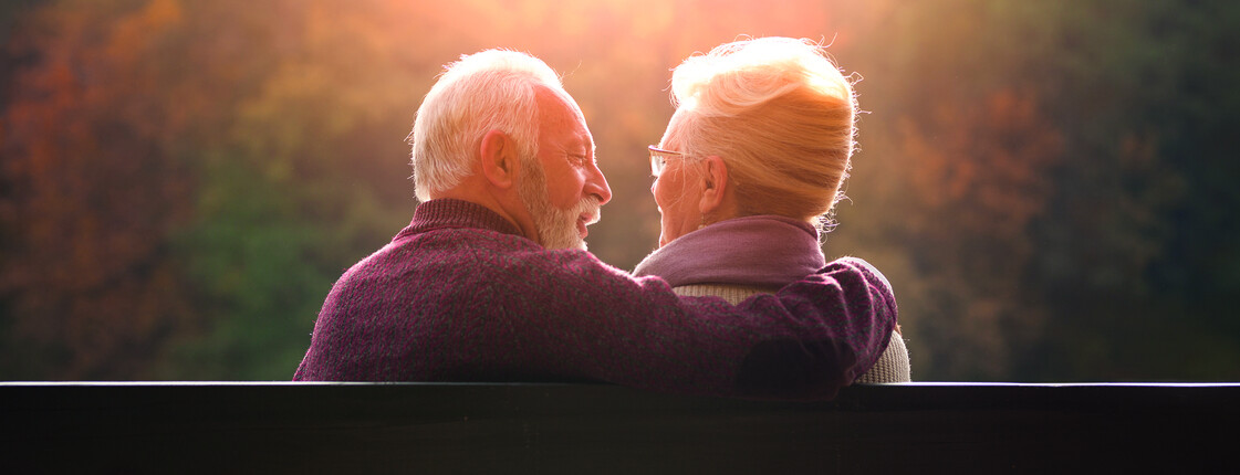Senior,Couple,Sitting,On,Bench,In,Autumn,Park,And,Looking