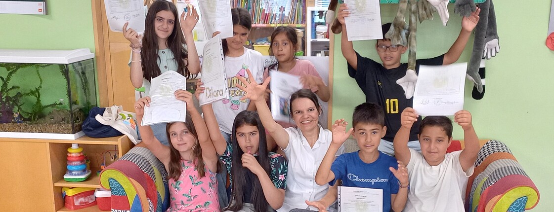 Kinder und Lehrerin mit Urkunden in einem Klassenzimmer