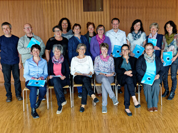 Eine Zertifikatsverleihung von Hospiz Vorarlberg. Sie sitzen und stehen für ein Gruppenfoto zusammen. 