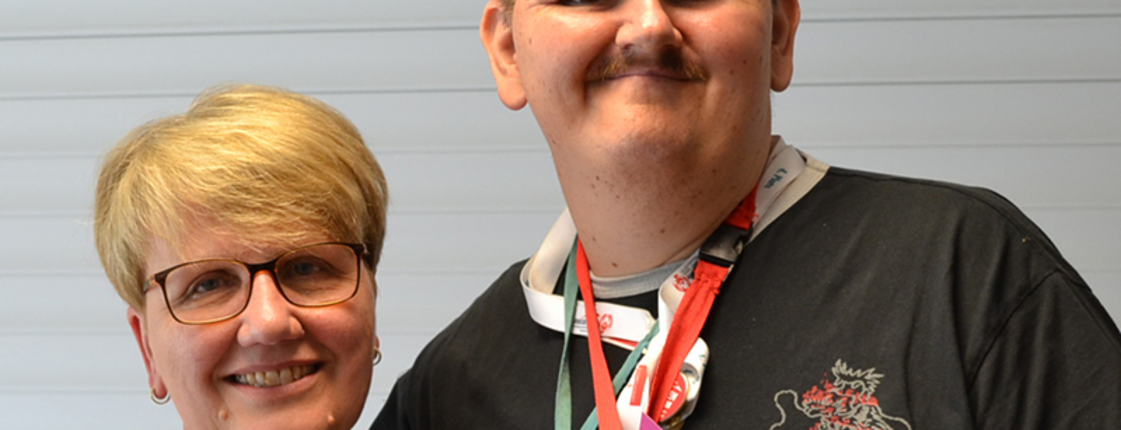 Ein Mensch mit Beeinträchtigung steht neben einer Frau
