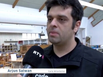 RTV im Interview mit carla-Mitarbeiter Arjun Salwan. Er trägt  kurze schwarze Haare und ebenfalls ein schwarzes Polo. 
