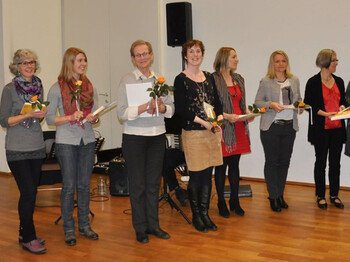 Lesepaten halten eine Rose in der Hand und lachen in die Kamera.