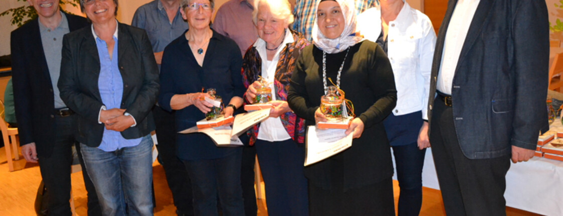 Ehrung von Freiwilligen. Ein Gruppenfoto von mehreren Menschen in einem hellen Raum.