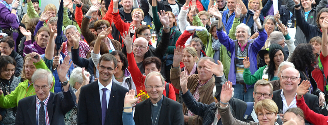 Etliche Mitwirkende der Caritas versammeln sich zur 90 Jahr Feier der Caritas Vorarlberg. Sie sind eine Menschenmenge von geschätzten 50 Menschen. 
