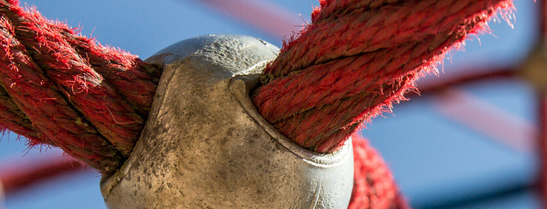 Eine Nahaufnahme von roten Seilen, die zu einem Netz verknüpft sind. 