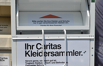 Einer der ca. 400 Kleidercontainer der Caritas in Vorarlberg. Er ist in beige gehalten. 