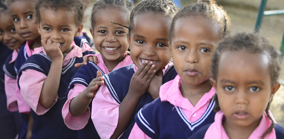 Junge äthiopische Mädchen, die allesamt das gleiche Schicksal teilen, Straßenkinder zu sein, sind auf dem Weg in die Schule. Sie tragen alle ein blau-pinke Schuluniform. 