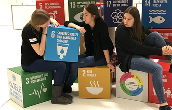 Drei Jugendbotschafterinnen mit den SDGs als überlebensgroße Würfel.