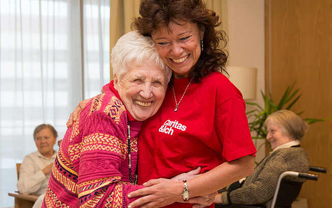Ältere Frau (links) umarmt Caritas Mitarbeiterin (rechts im Bild)